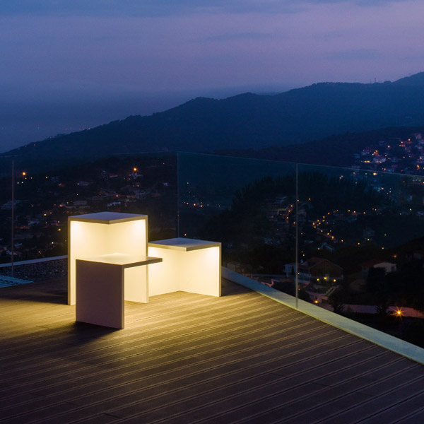 Outdoor Illuminated Furniture: Minimalist illuminated table & seats on a contemporary balcony overlooking a city and mountains at night