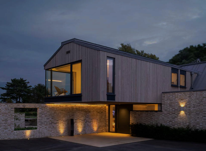 Modern minimalist cantilever house at night with smart home lighting and outdoor landscape lighting