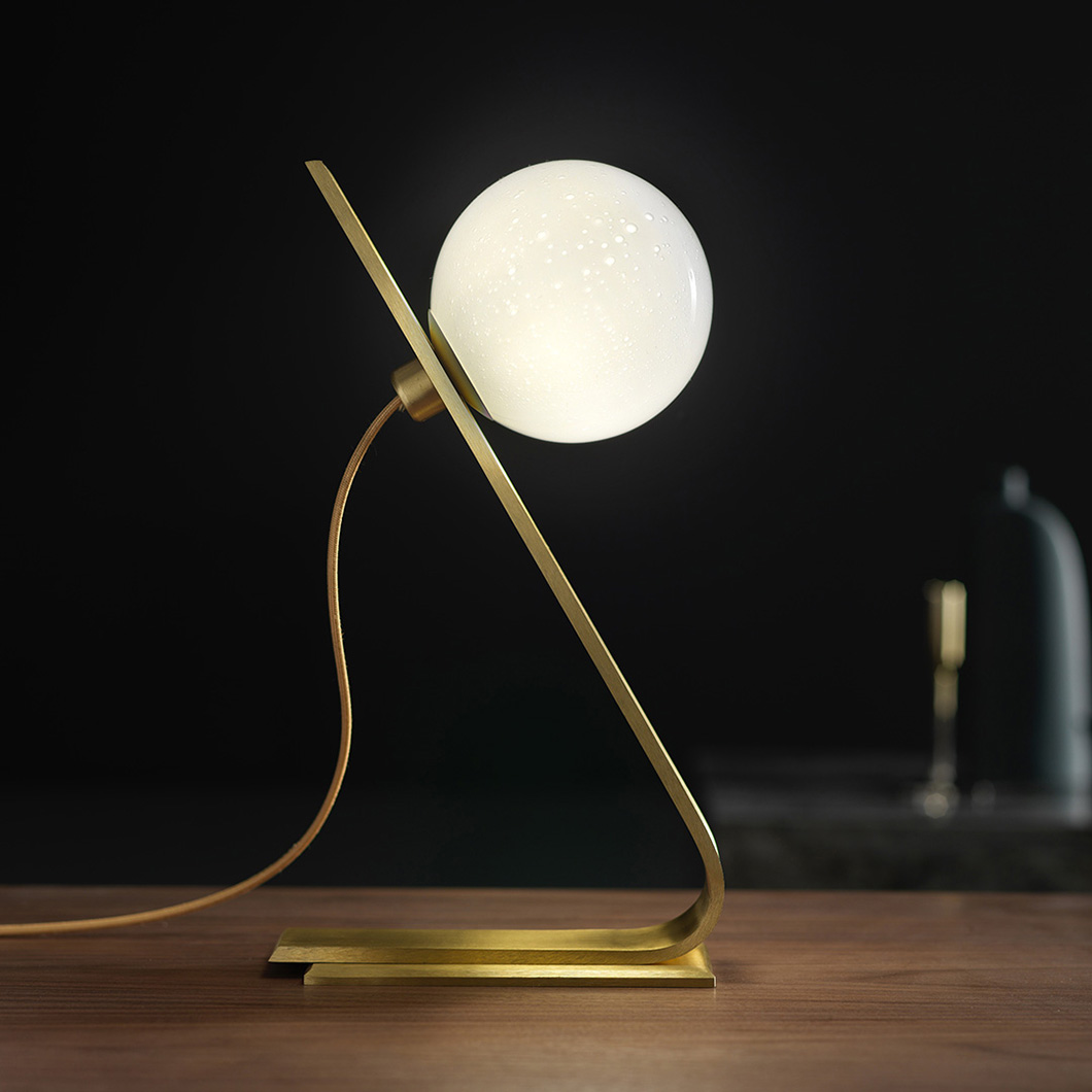 Side on view of Esperia Daphne Table Lamp, highlighting brass structure and milky white sphere lampshade