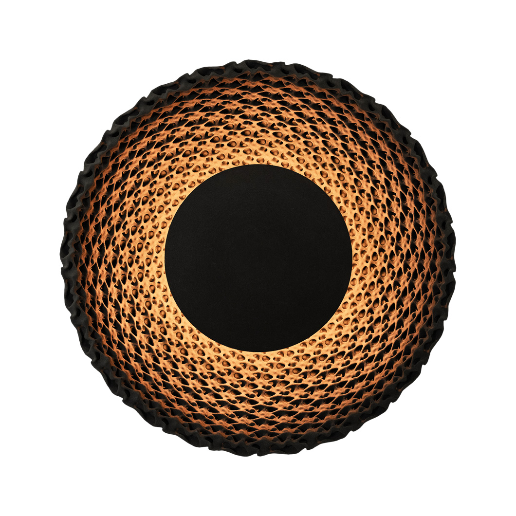 Large round wall light made from black quartz sand casting a soft, warm glow