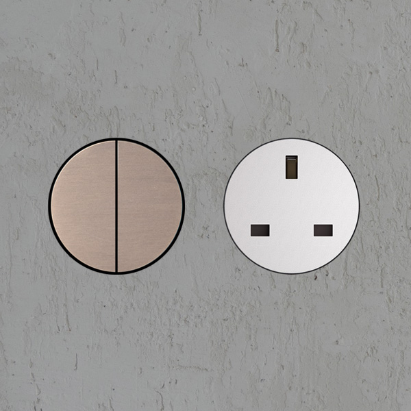 Sockets & Switches: Architectural brushed bronze round wall switch and white round switchless UK power socket installed in plastered wall